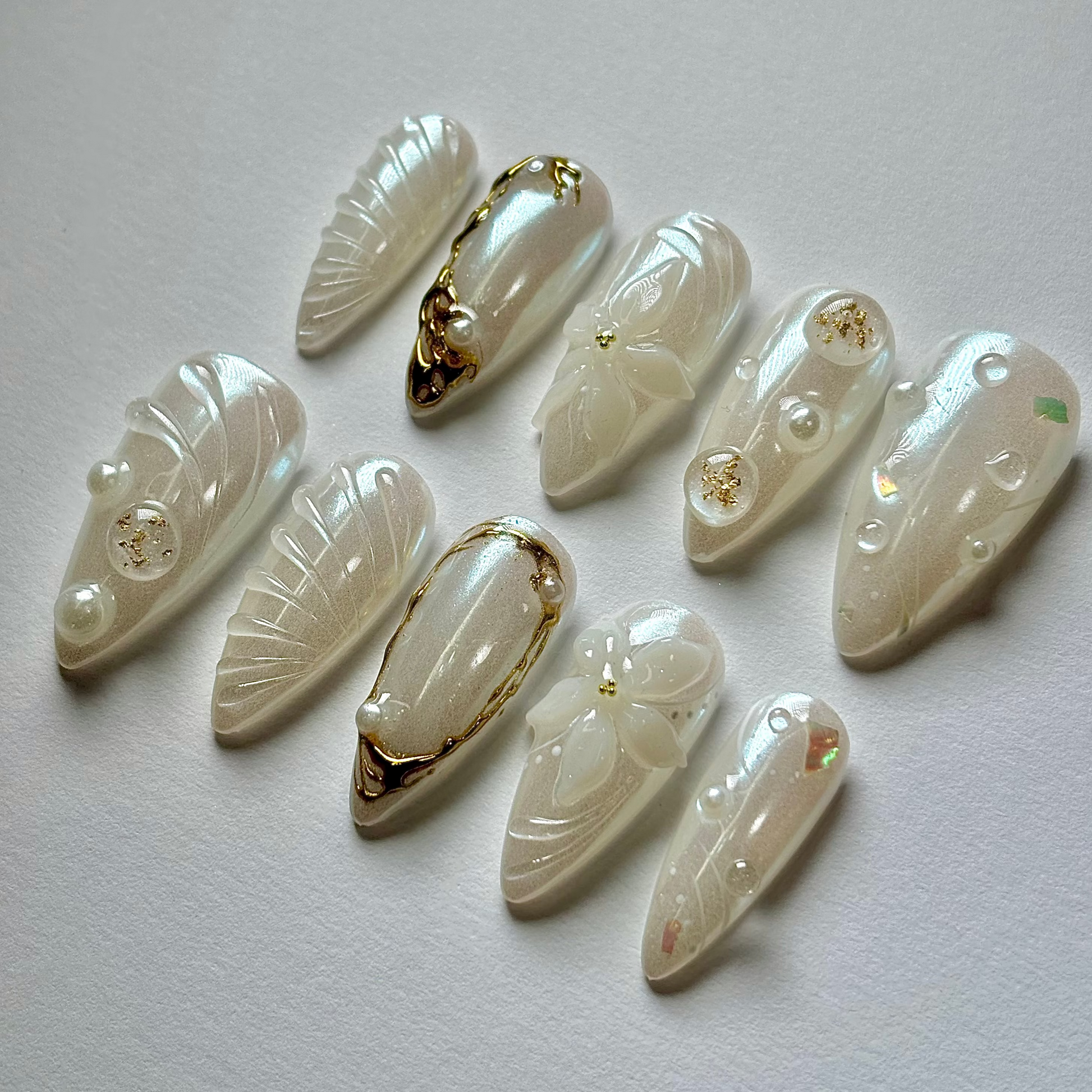 Set of decorative nail extensions with gold accents on a light gray background
