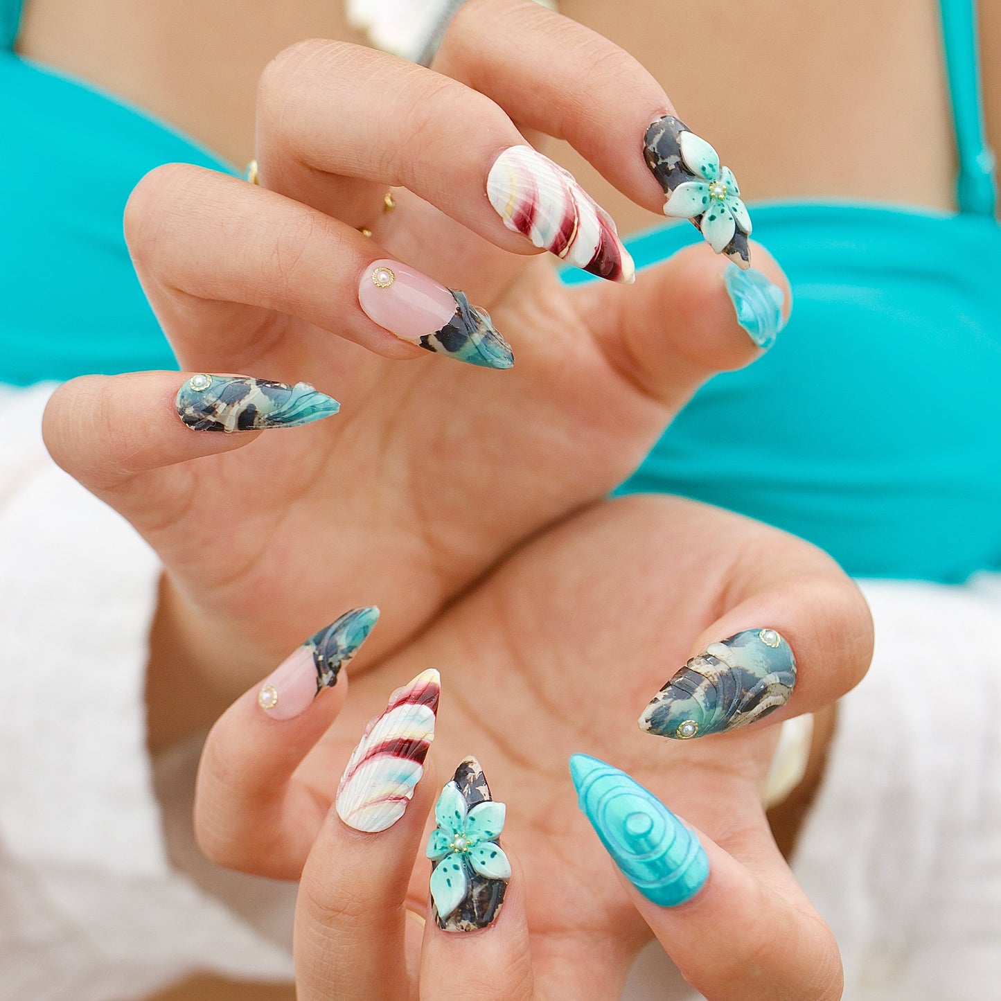 Close-up of a hand with colorful nail art wearing a turquoise bikini.